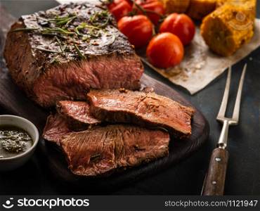 Sliced Roast beef on cutting board with grilled vegetables, close-up.