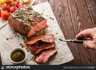 Sliced Roast beef on white paper on wooden table with grilled vegetables