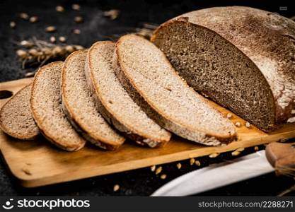Sliced rye bread on a cutting board. On a black background. High quality photo. Sliced rye bread on a cutting board.
