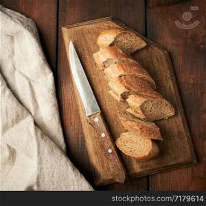 sliced rye flour baguette on a wooden cutting board, top view