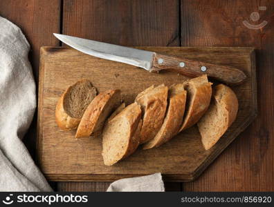 sliced rye flour baguette on a wooden cutting board, top view