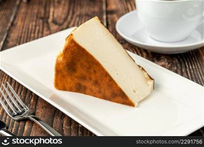 Sliced san sebastian cheesecake with coffee on wooden table