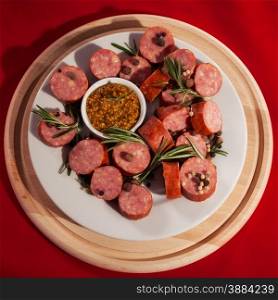 sliced sausages on a plate with rosemary and pepper