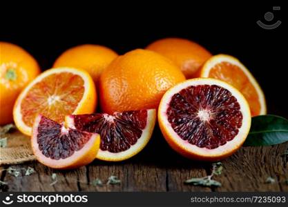 Sliced Sicilian Blood oranges fruits over old dark wooden background. Top view.