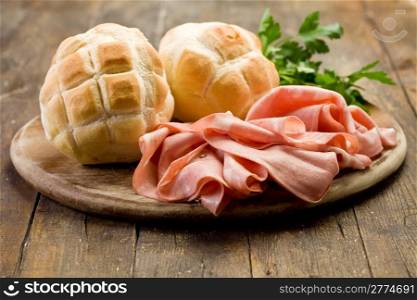 Sliced soft mortadella sausage on wooden table with bread