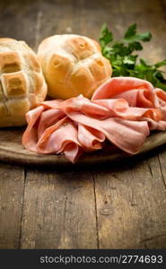 Sliced soft mortadella sausage on wooden table with bread