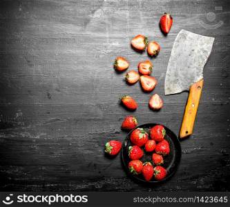 Sliced strawberries with the old hatchet. On the black wooden table.. Sliced strawberries with the old hatchet.