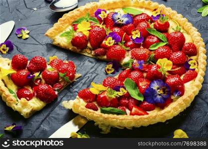 Sliced strawberry pie decorated with edible flowers and mint.Trendy summer berry pie. Open summer pie or cake with berries