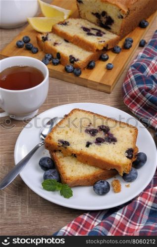 sliced summer cake with blueberry with a cup of tea on the table