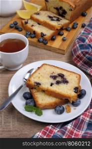 sliced summer cake with blueberry with a cup of tea on the table