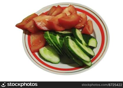 Sliced tomatoes and cocumbers on the round plate isolated