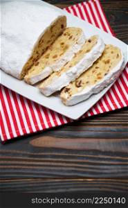 Sliced Traditional Christmas stollen cake with marzipan and dried fruit on wooden background. High quality photo. Sliced Traditional Christmas stollen cake with marzipan and dried fruit on wooden background
