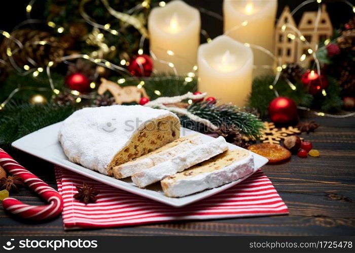 Sliced Traditional Christmas stollen cake with marzipan and New Year decorations on wooden background. High quality photo. Sliced Traditional Christmas stollen cake with marzipan and New Year decorations on wooden background