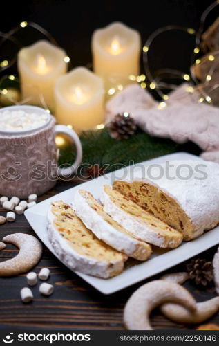 Sliced Traditional Christmas stollen cake with marzipan and New Year decorations on wooden background. High quality photo. Sliced Traditional Christmas stollen cake with marzipan and New Year decorations on wooden background