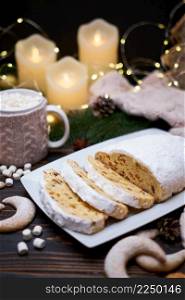 Sliced Traditional Christmas stollen cake with marzipan and New Year decorations on wooden background. High quality photo. Sliced Traditional Christmas stollen cake with marzipan and New Year decorations on wooden background