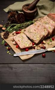 Sliced Traditional French terrine covered with bacon on dark wooden background. High quality photo. Sliced Traditional French terrine covered with bacon on dark wooden background