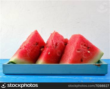 sliced triangles ripe red round watermelon with seeds on a blue background