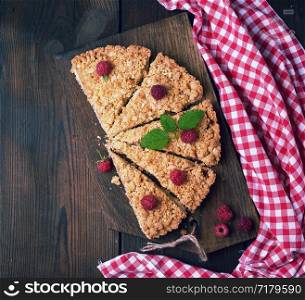 sliced triangular pieces of crumble pie with apples on a brown wooden board, top view