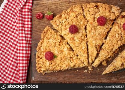 sliced triangular pieces of crumble pie with apples on a brown wooden board, top view