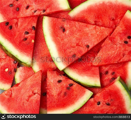 sliced triangular slices of ripe red watermelon with brown seeds, bright summer texture backdrop