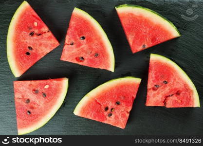 Sliced watermelon on black slate surface. Top view.. Sliced watermelon black slate background