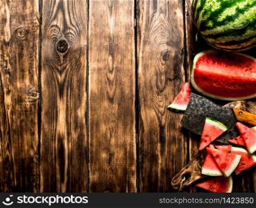 Sliced watermelon with an axe. On wooden background.. Sliced watermelon with an axe.