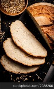 Sliced wheat bread on a cutting board. On a black background. High quality photo. Sliced wheat bread on a cutting board. 
