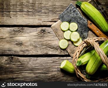 Sliced zucchini and an old hatchet . On wooden background.. Sliced zucchini and an old hatchet .