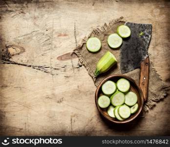 Sliced zucchini and an old hatchet . On wooden background.. Sliced zucchini and an old hatchet .