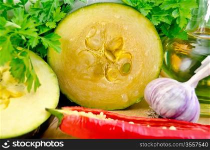 Sliced zucchini, garlic, hot red pepper, a bottle of vegetable oil, parsley on a wooden board