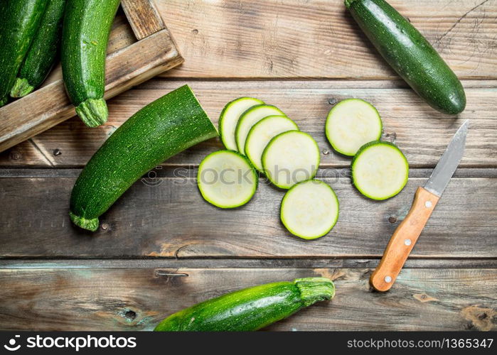 Sliced zucchini with a knife. On wooden background. Sliced zucchini with a knife.