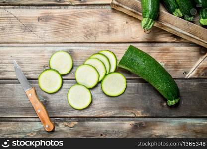 Sliced zucchini with a knife. On wooden background. Sliced zucchini with a knife.