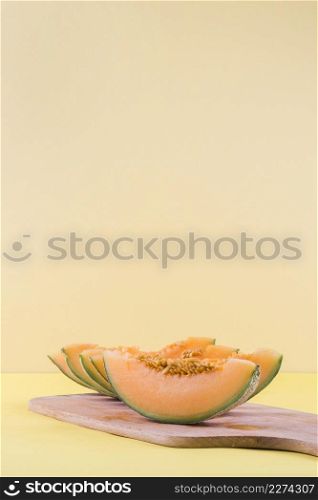 slices cantaloupe wooden chopping board against beige backdrop
