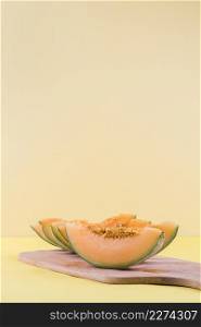 slices cantaloupe wooden chopping board against beige backdrop