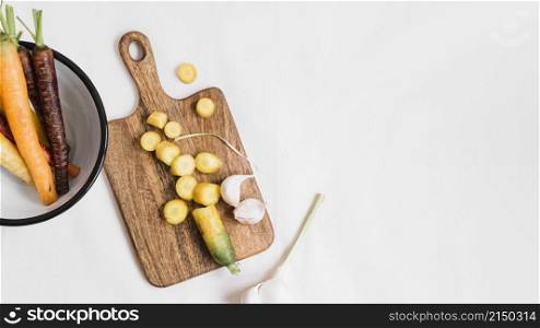 slices carrot garlic cloves chopping board white background