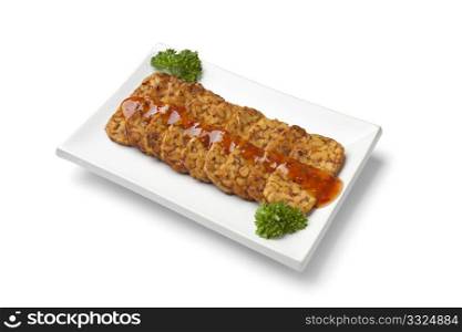 Slices fried tempeh with chili sauce on a dish
