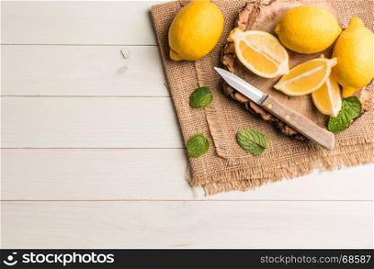 Slices, half fresh juicy lemon with mint leaves and knife on the vintage wooden table. Top view with copy space.