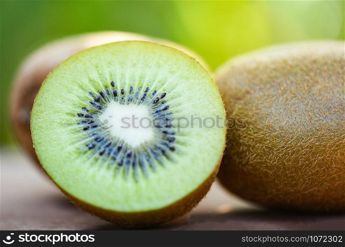 slices kiwi close up and fresh whole kiwi fruit on wooden and nature green background