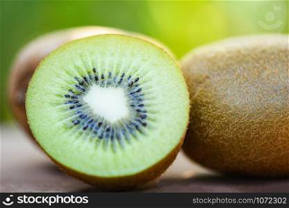 slices kiwi close up and fresh whole kiwi fruit on wooden and nature green background