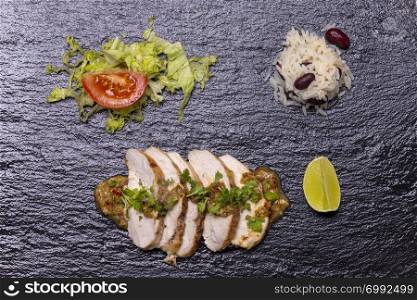slices of a grilled chicken on slate