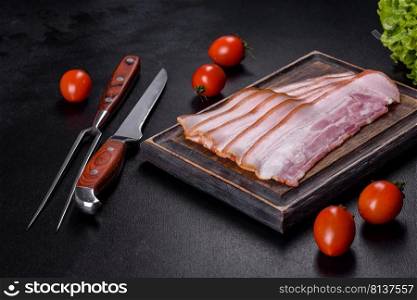 Slices of bacon on a wooden cutting Board. Pork meat. Black background. Top view. Slices of bacon on a wooden cutting Board. Pork meat