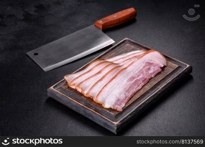 Slices of bacon on a wooden cutting Board. Pork meat. Black background. Top view. Slices of bacon on a wooden cutting Board. Pork meat