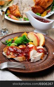 Slices of baked turkey with cranberry-orange sauce with fruit and vegetable garnish