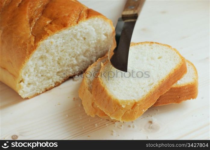 Slices of bread and knife on a wooden table. Bread