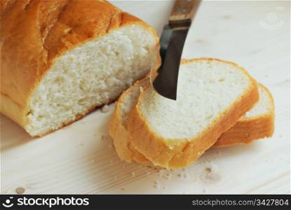 Slices of bread and knife on a wooden table. Bread