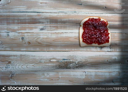 Slices of bread, sandwich with strawberry jam on old wooden table.