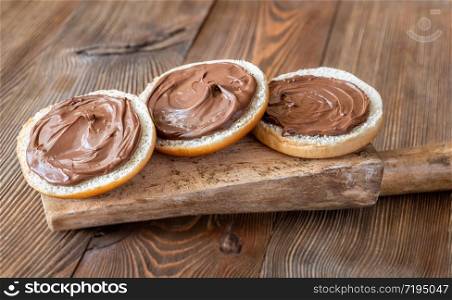 Slices of bread with chocolate paste on wooden board