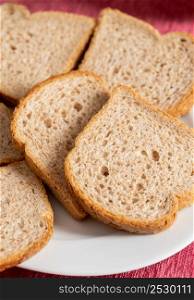 Slices of brown bread baked from wheat flour on a white plate.