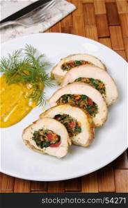 Slices of chicken breast stuffed with spinach, carrot, pepper, tomato on a plate