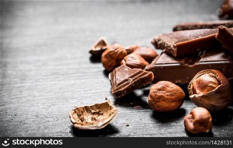 Slices of chocolate with hazelnuts. On the black wooden table.. Slices of chocolate with hazelnuts.